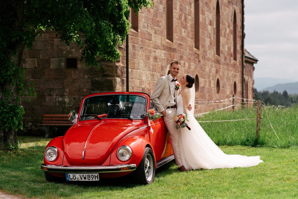Brautpaar auf einer Bergwiese mit rotem Käfer – Hochzeitsfotografie Mosipictures