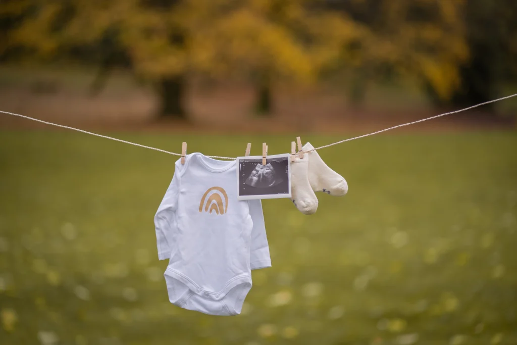 Babykleidung und Ultraschallbild an einer Wäscheleine im Park – Mosipictures