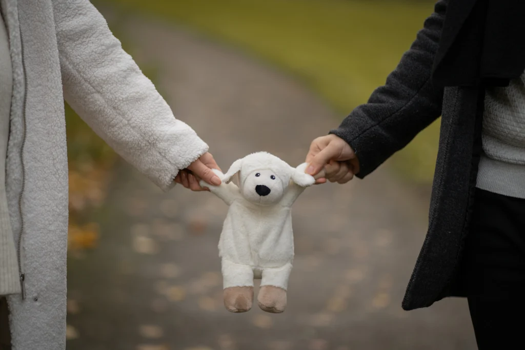 Werdende Eltern halten gemeinsam ein Kuscheltier – Babybauch-Shooting von Mosipictures