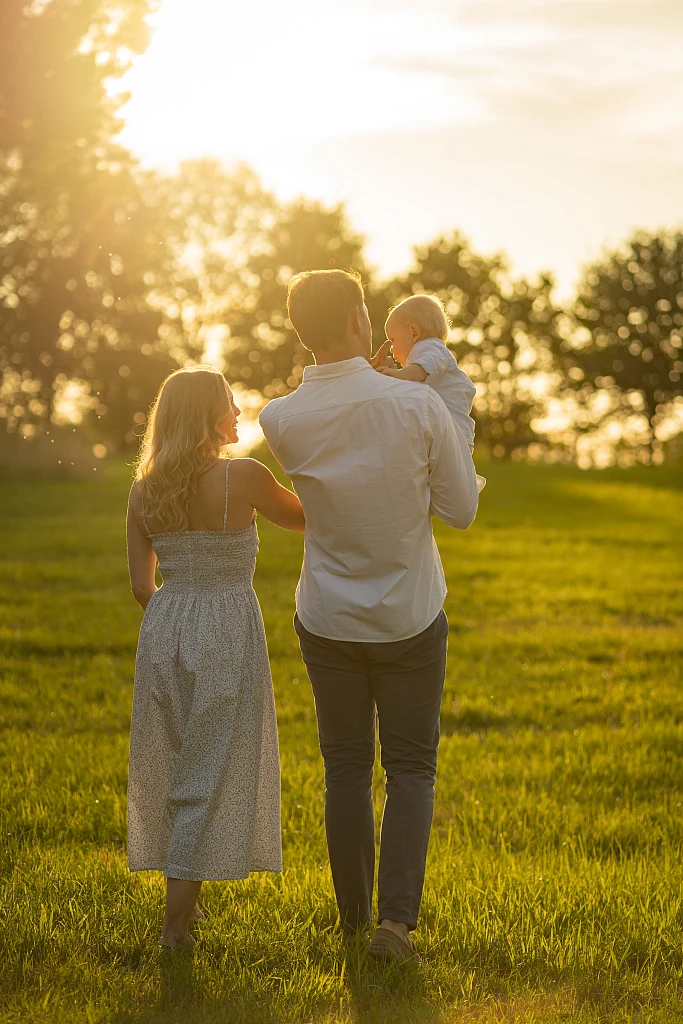 Familie geht Hand in Hand über eine Wiese in der Abendsonne – Mosipictures
