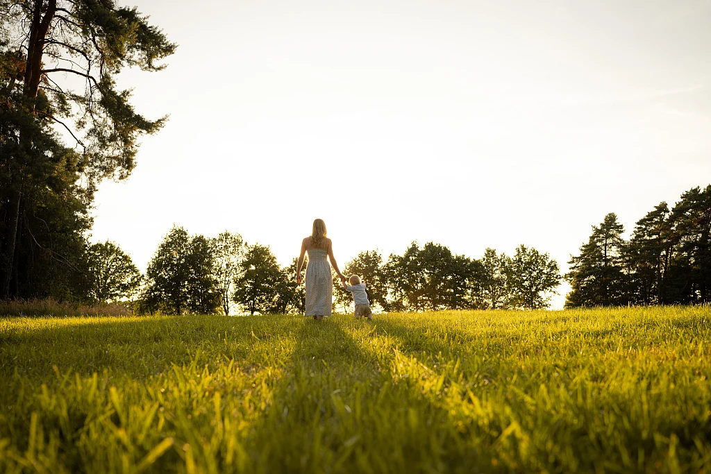 Familie als kleine Silhouette auf einer weiten Wiese im Abendlicht – Mosipictures