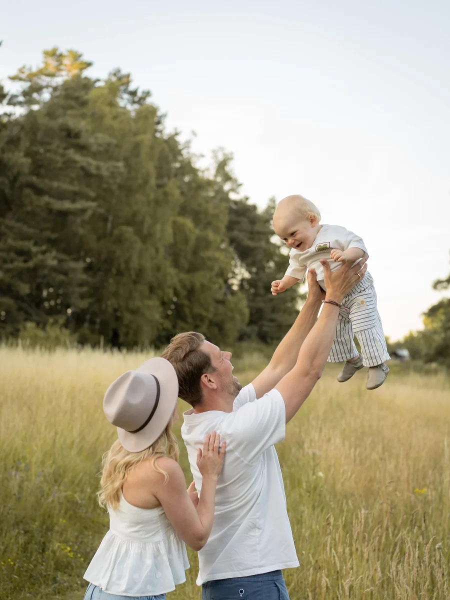 Vater hebt das Kind in die Luft, die Mutter schaut lachend zu – Mosipictures
