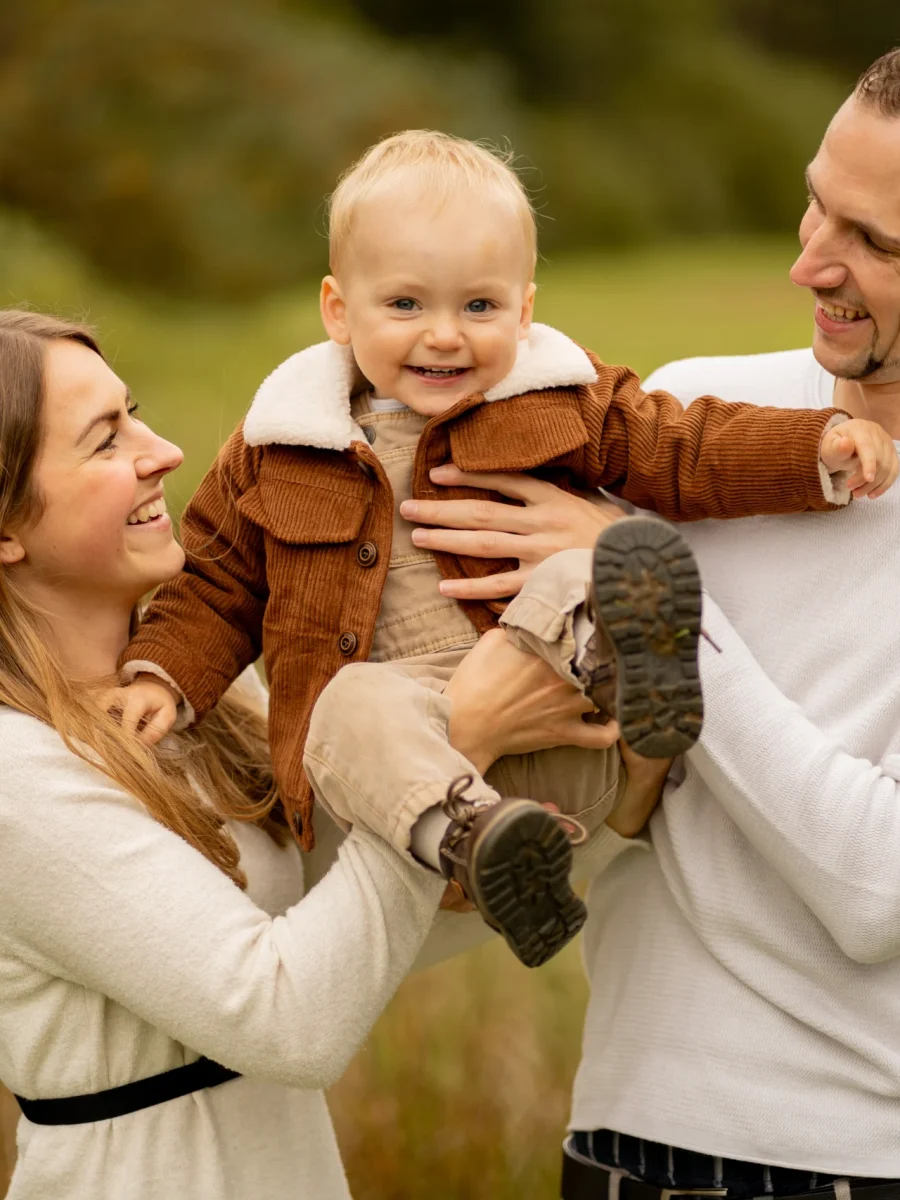 Eltern heben ihren lachenden Sohn in die Luft – Familienshooting von Mosipictures