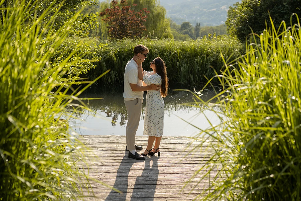 Paar auf einem Holzsteg am Teich zwischen hohen Gräsern – Paarshooting von Mosipictures