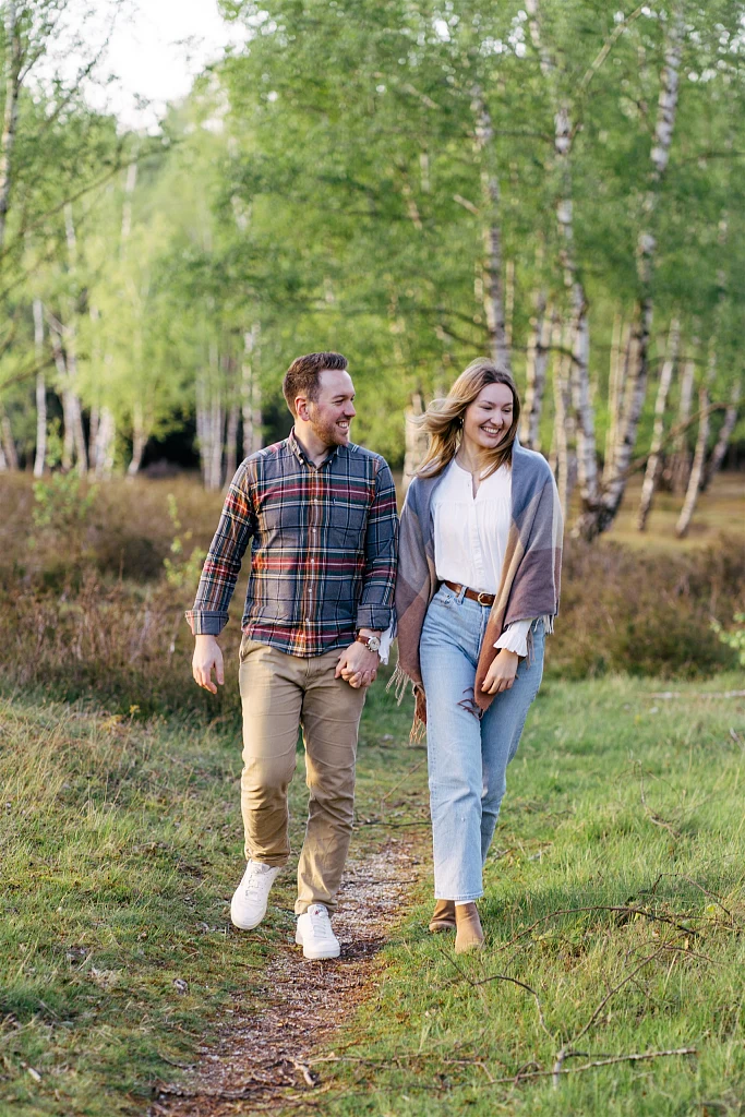 Paar spaziert Hand in Hand auf einem Weg durch Heide und Birken – Mosipictures